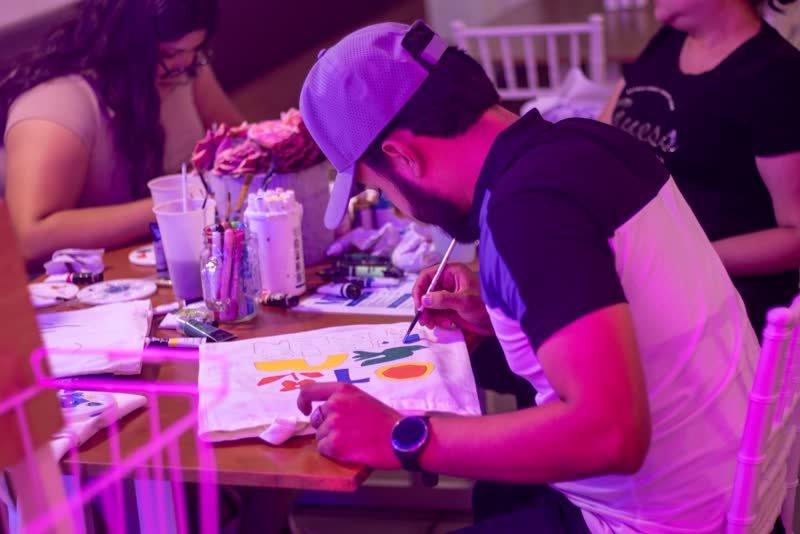 Participante pintando una tote bag con pincel fino