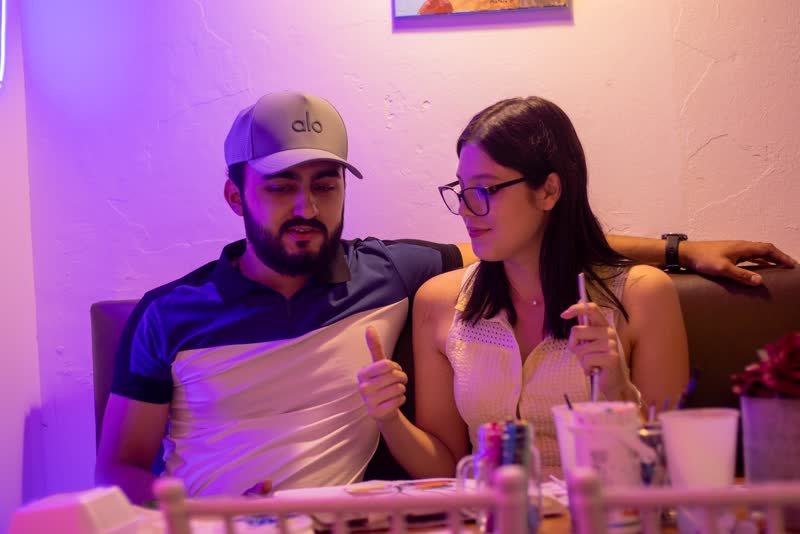 Pareja riendo mientras pinta en el taller