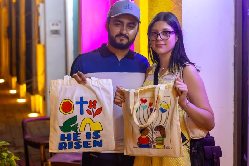 Pareja mostrando las tote bags que pintaron en el taller
